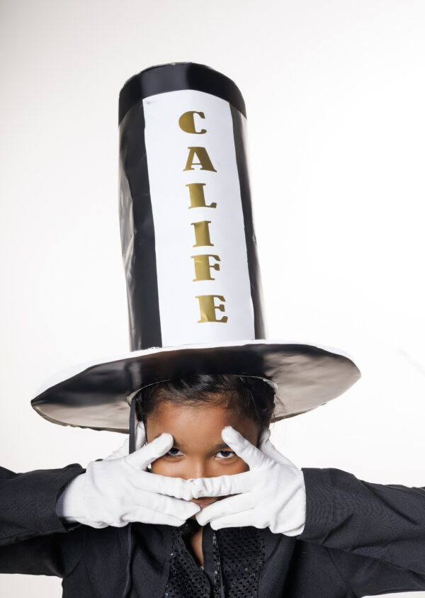 Niña vestida de Calife, personaje del carnaval dominicano, con sombrero alto y guantes blancos