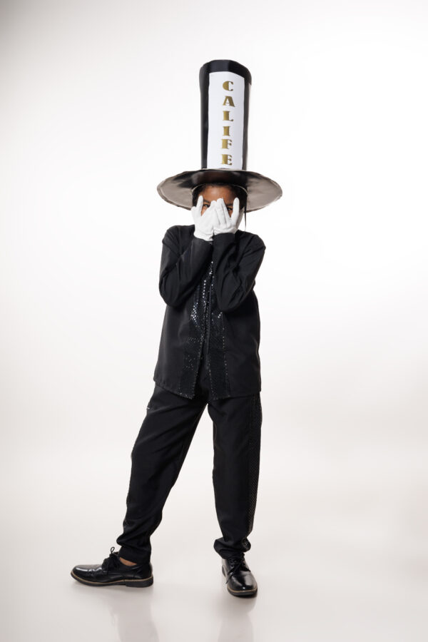 Niña usando traje de Calife infantil del carnaval dominicano, con sombrero alto negro y guantes blancos